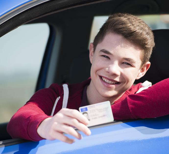 Joven conductor mostrando su carné en su coche azul