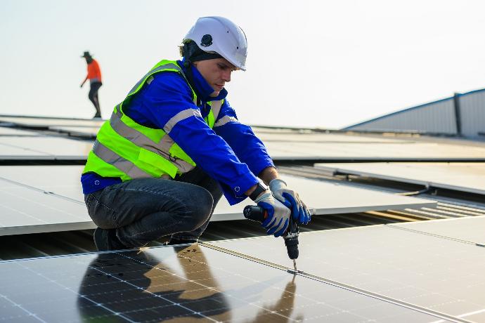Trabajador colocando una placa fotovoltaica en un tejado